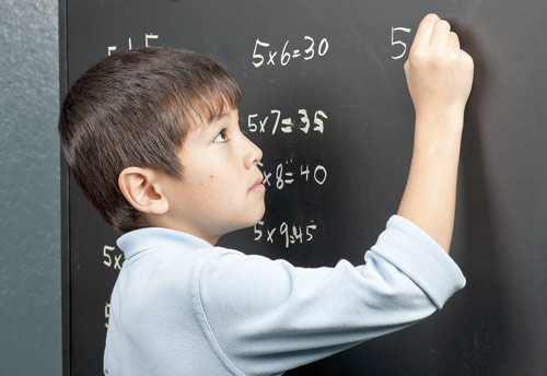 Boy multiplying on chalkboard